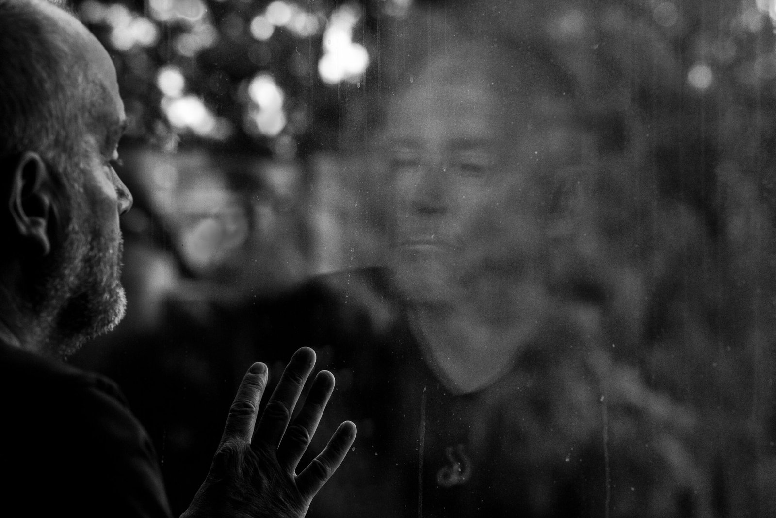 Un hombre mayor mirando su reflejo en una ventana