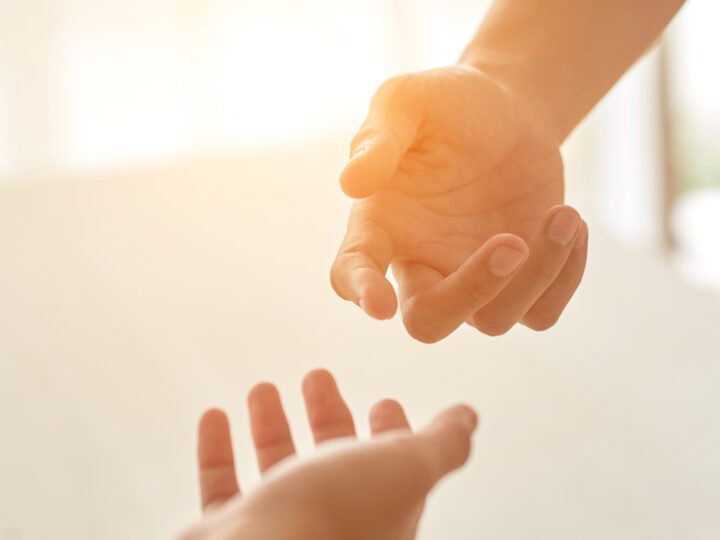 Two hands reaching toward each other in soft, warm light