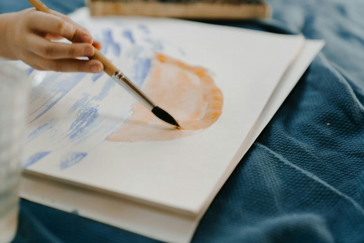Una mano pintando con un pincel sobre papel durante una sesión de arteterapia